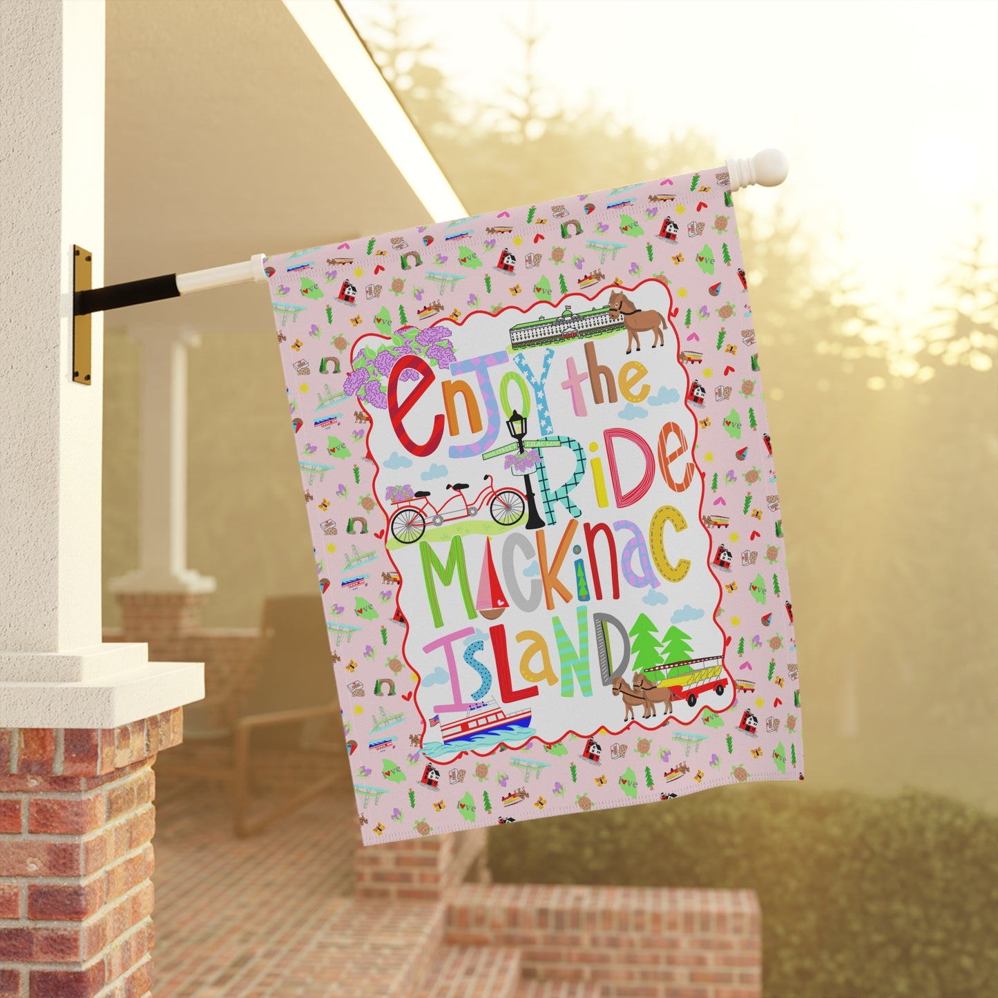 Mackinac Island garden flag featuring whimsical "Enjoy the Ride" artwork with island-inspired illustrations.