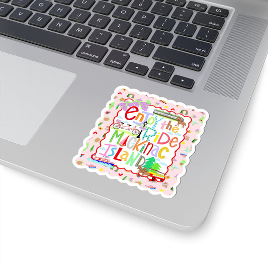 A square die-cut sticker with a scalloped border, featuring the text 'Enjoy the Muckin' Island' in colorful retro lettering, placed on the silver surface of a laptop next to the keyboard.