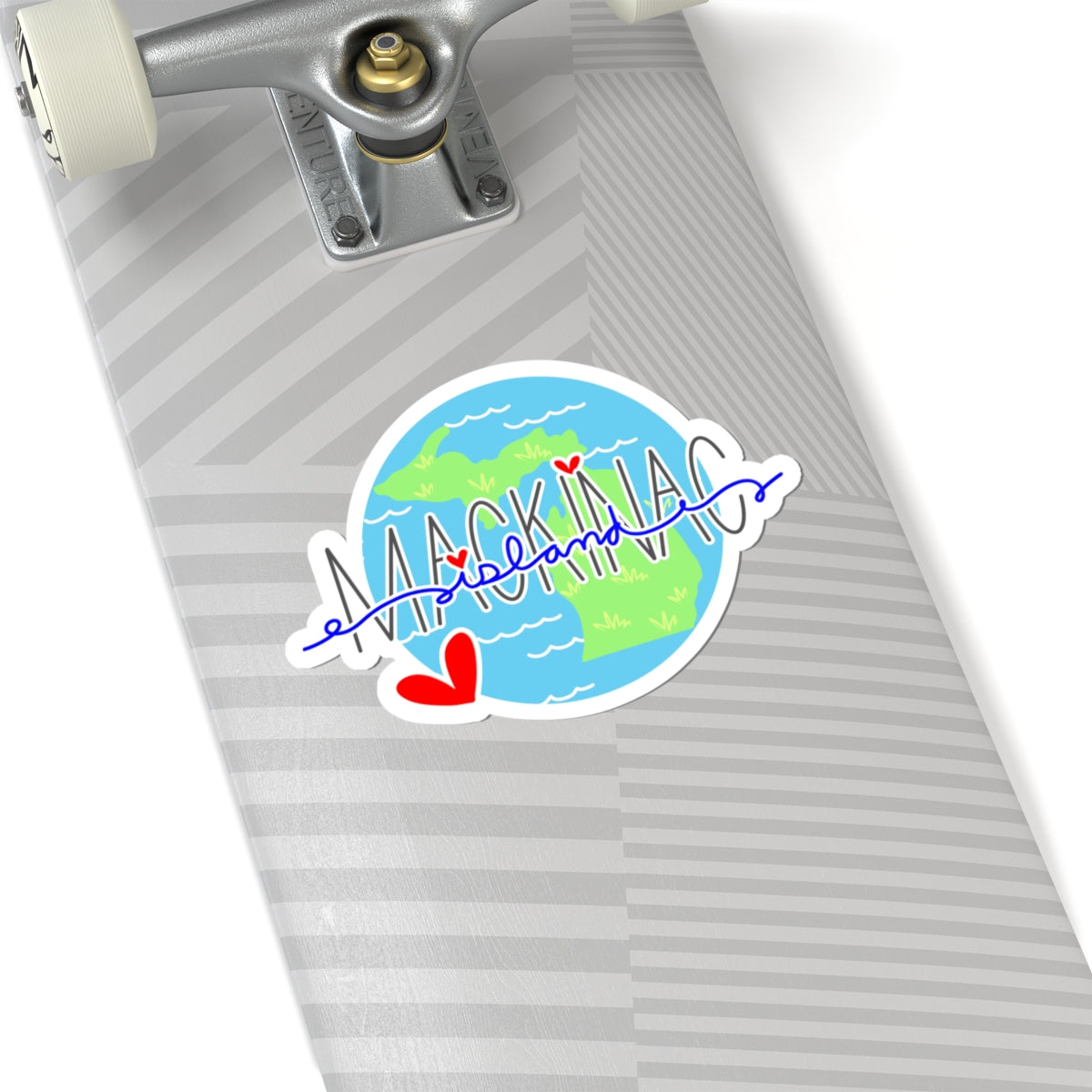 A die-cut sticker featuring a stylized map of Florida with the word 'MACKINAC' in blue script and red hearts, shown on a gray skateboard deck.