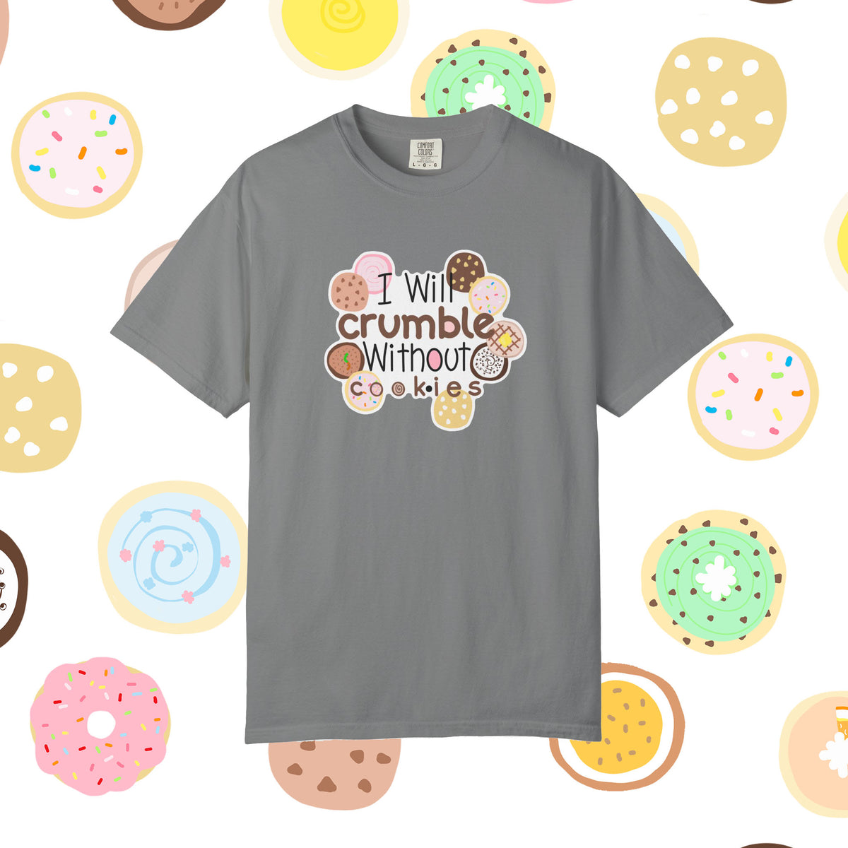 A gray short-sleeve t-shirt with a graphic that reads 'I Will crumble Without cookies' surrounded by illustrated donuts, displayed against a white background patterned with donuts.