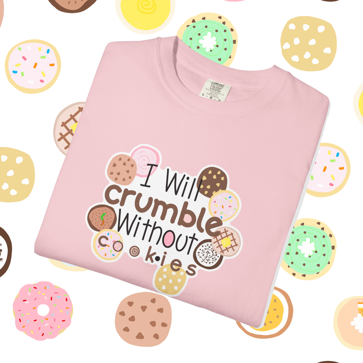 I Will Crumble for Cookies T-shirt, cute cookie lover gift for bakers and crumble cookie lovers as a folded light pink t shirt with a graphic that reads 'I Will crumble Without cookies' surrounded by illustrated donuts, shown on a white background with a repeating pattern of donuts.